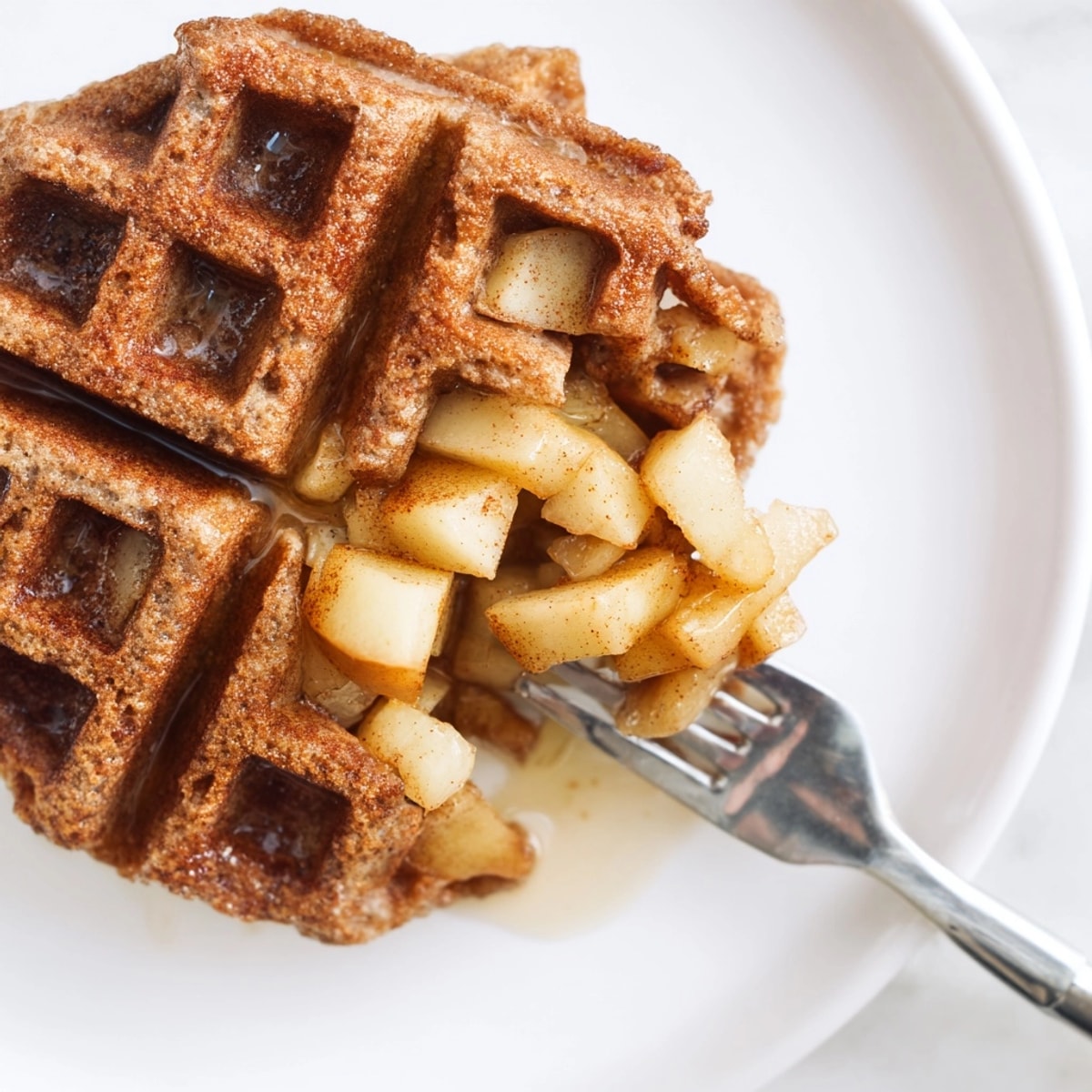 Close-up shows fluffy texture and juicy apples in these delicious Cinnamon Apple Protein Waffles.
