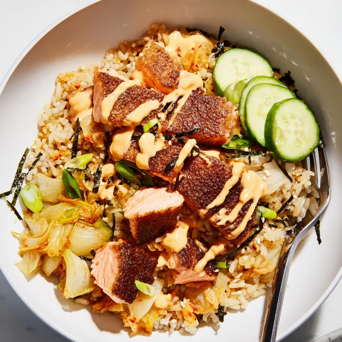 Delicious crispy salmon rice bowl featuring golden rice, spicy mayo, and garlic chips.  