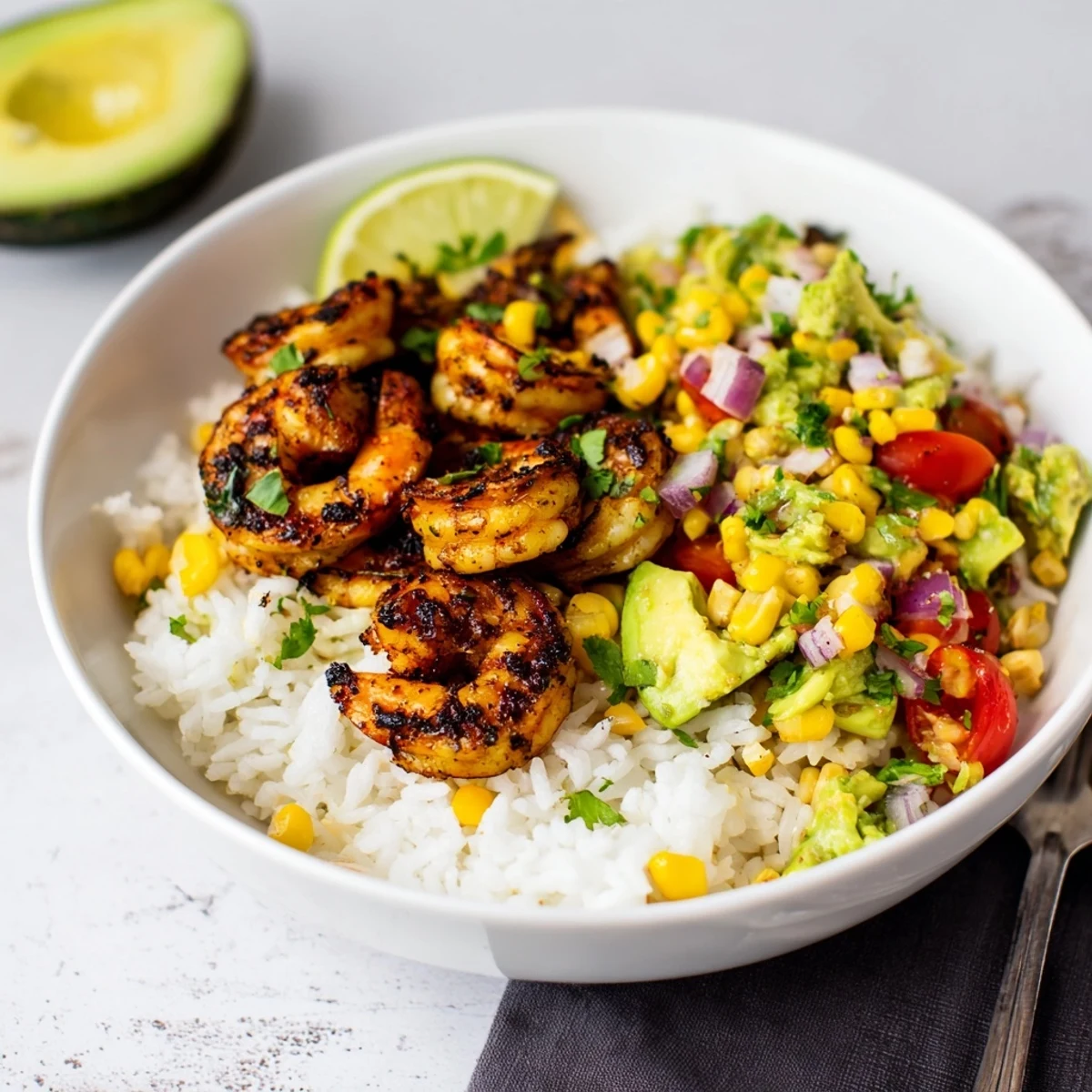 Blackened shrimp bowl featuring spicy shrimp atop fluffy rice with creamy avocado salsa.