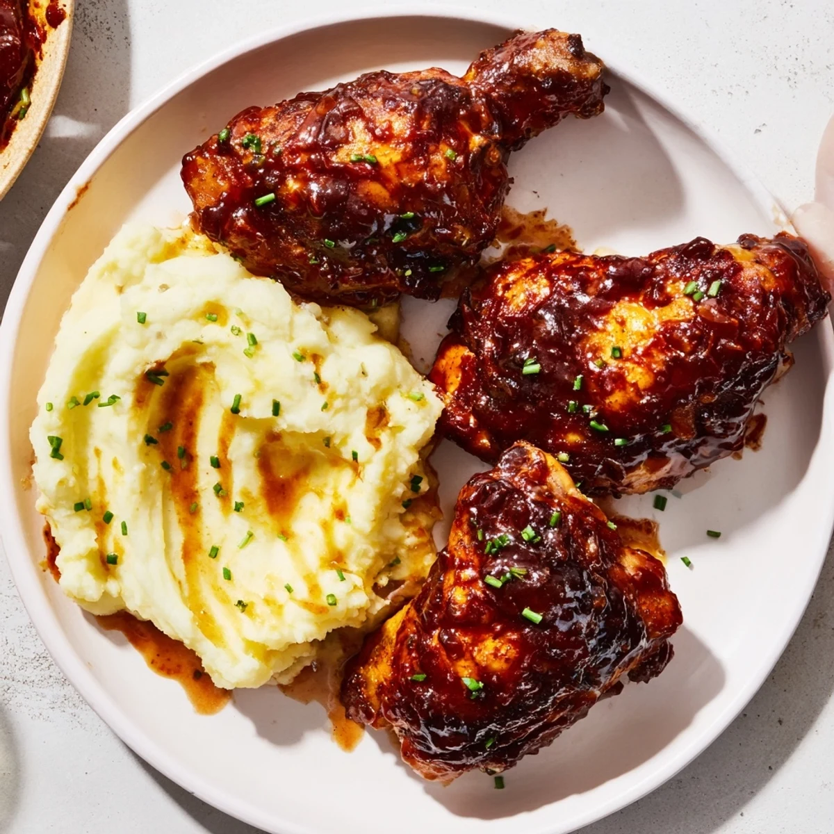 Honey BBQ Chicken Thighs with glistening sauce next to creamy garlic mashed potatoes, a comforting dinner.