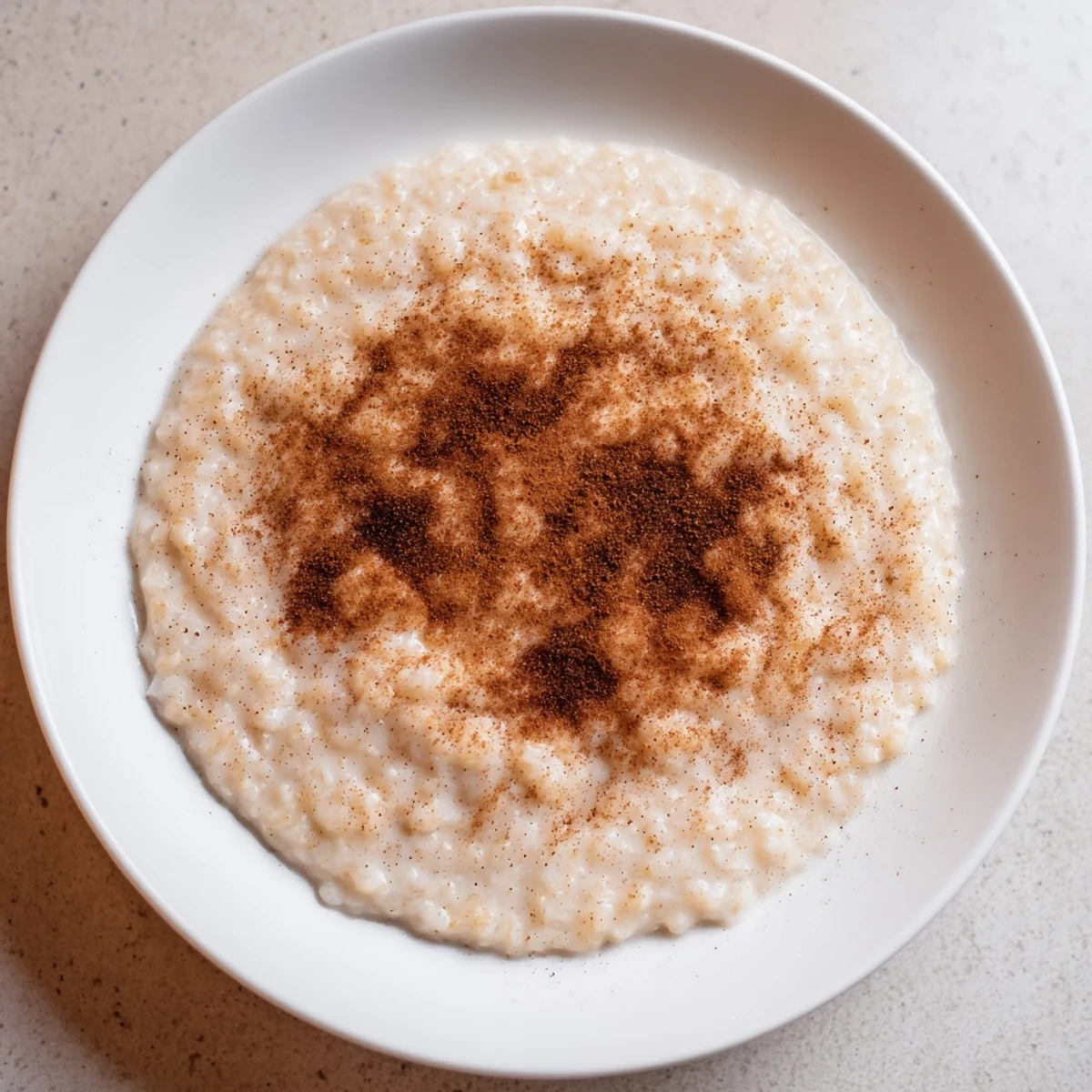 A warm bowl of creamy Rice Pudding with Leftover Rice, finished with a generous cinnamon sprinkle.