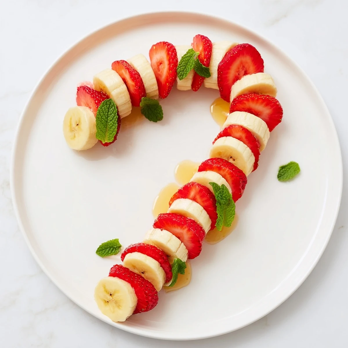 A beautifully arranged strawberry and banana candy cane, ready to be enjoyed as a refreshing snack.