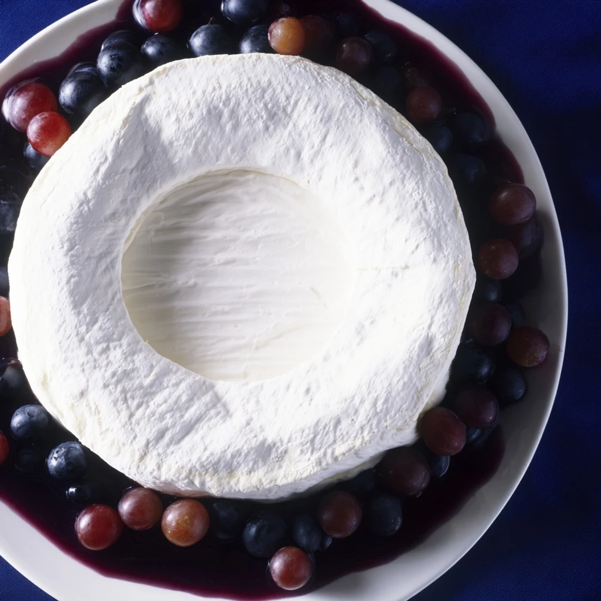Floating Island appetizer: a creamy Brie cheese wheel sits atop blue yogurt, circled by grapes.