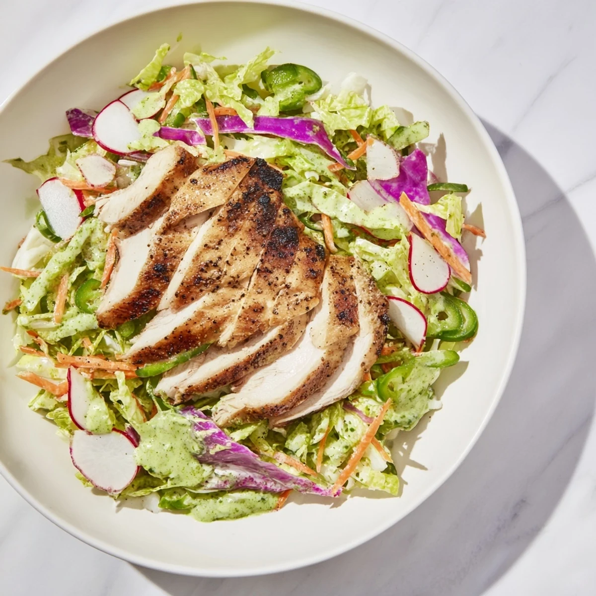 Green Goddess Cabbage Slaw with Grilled Chicken: A colorful plate of slaw topped with sliced juicy chicken.