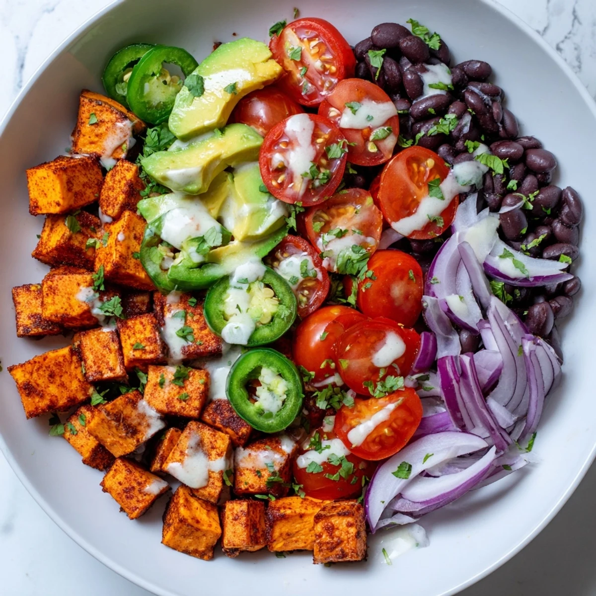 Roasted sweet potato taco bowls, a colorful vegan meal served with a bright lime dressing.