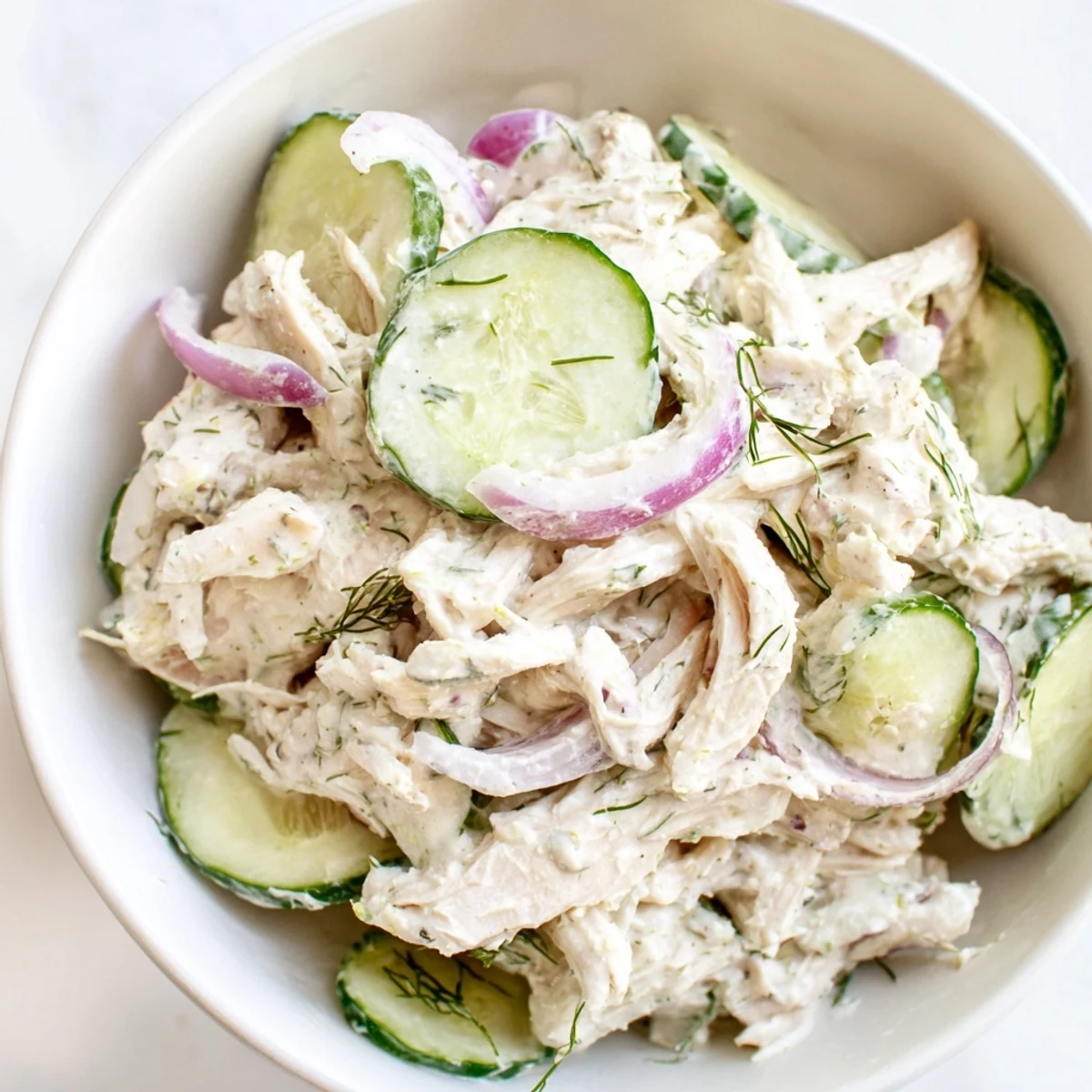 A bowl of Creamy Cucumber Chicken Salad with tender shredded chicken, crisp cucumber slices, and fresh dill garnish.