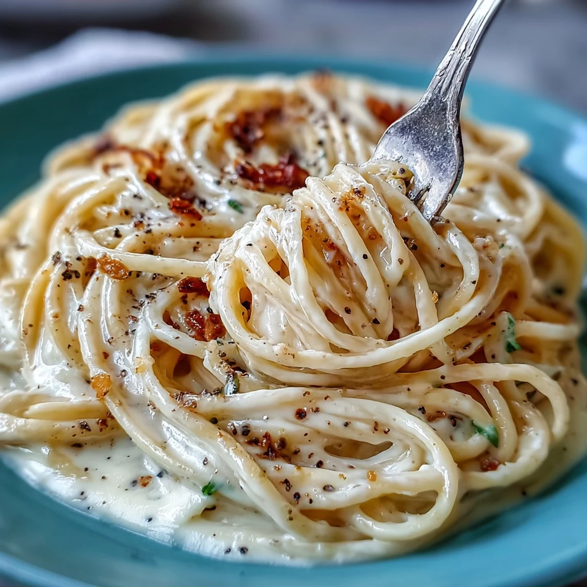 Close-up view of Cacio e Pepe on a fork, revealing the rich, savory cheese sauce clinging to the pasta with aromatic black pepper specks.