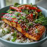 Close-up of Teriyaki Salmon Bowl showing tender salmon, crisp veggies, and sesame garnish on steaming rice.