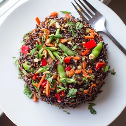 Close-up of delicious Thai Peanut Wild Rice Pilaf, garnished with fresh herbs and peanuts.