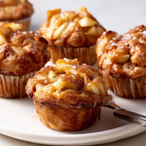 Warm cinnamon-swirled apple muffins topped with luscious caramel glaze, perfect for breakfast.  