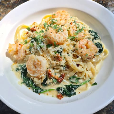 Golden, savory Tuscan Garlic Shrimp Pasta, perfect for a cozy Italian dinner, served with fresh herbs.