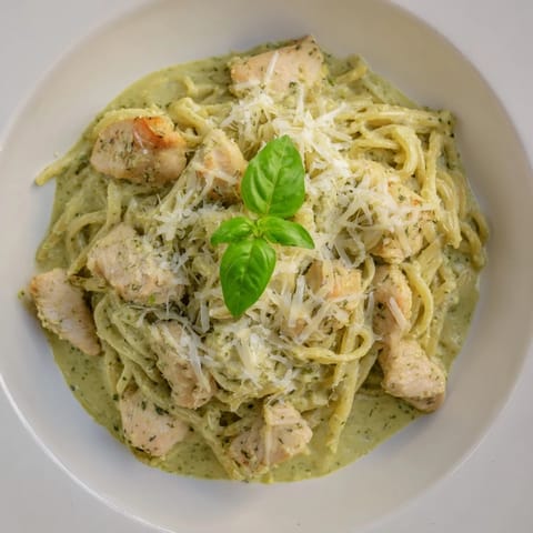 This photo shows a comforting bowl of creamy pesto penne & chicken, ready to be enjoyed.