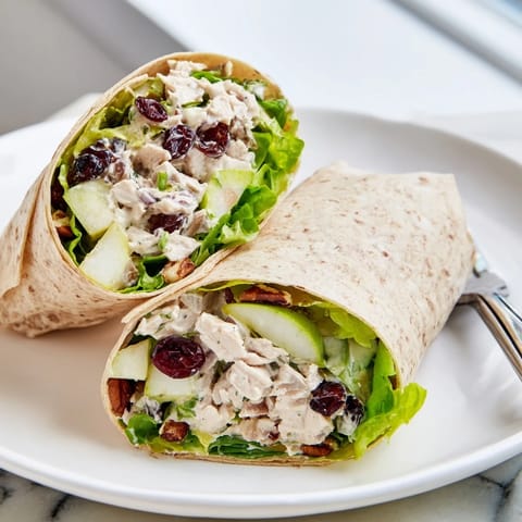 A cross-section shows the delicious layers of the Cranberry Pecan Chicken Salad Christmas Wrap, ready for a bite.
