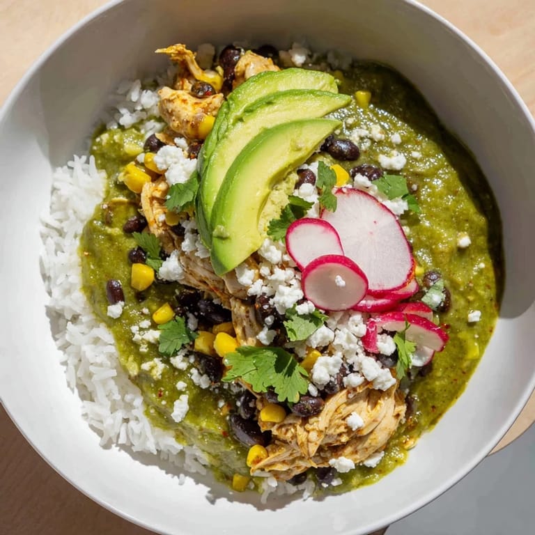 This close-up displays a delicious Green Enchilada Rice Bowl with fluffy rice and fresh, colorful garnishes.