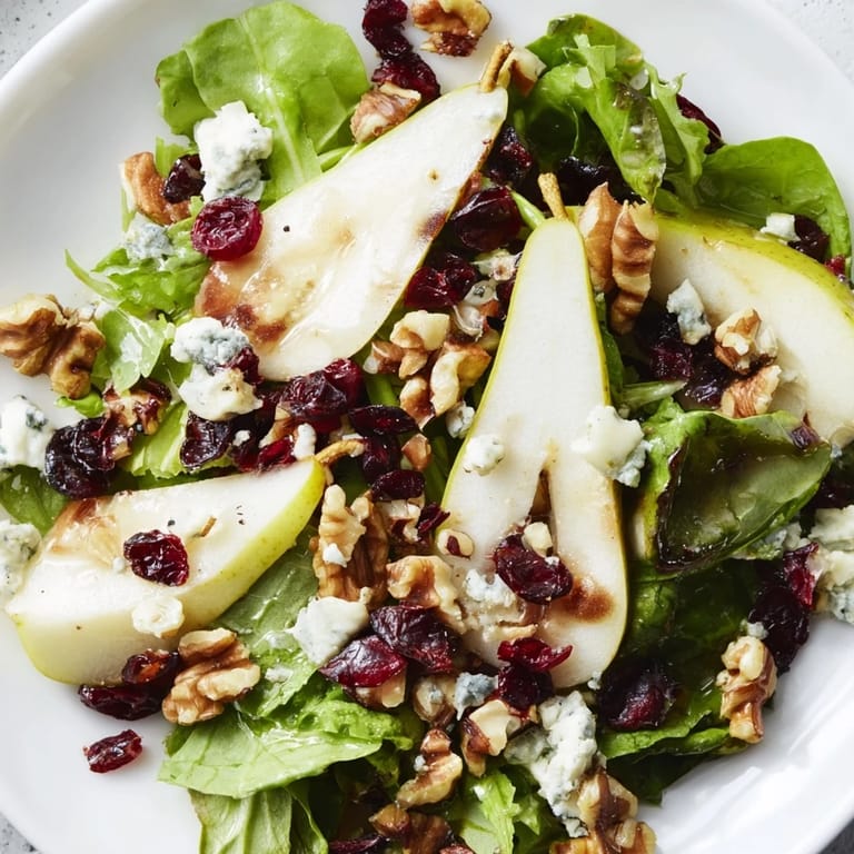 Pear Gorgonzola Salad combines sweet pear tangs with rich blue cheese and crunchy nuts over crisp arugula and spinach for an easy, elegant starter.  
