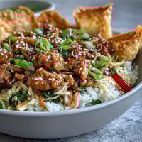 Golden brown crispy baked wonton strips crowning a bowl of Crispy Baked Egg Roll Chicken filled with savory ground chicken, crunchy cabbage, and fluffy rice.